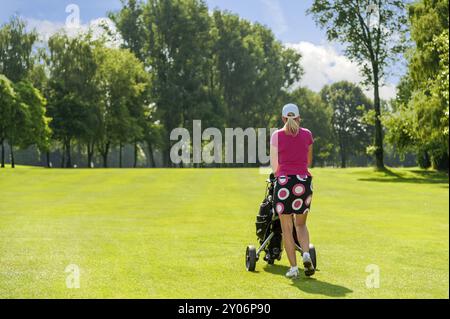 Rückansicht des Golfers mit Trolley auf dem Platz Stockfoto