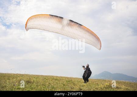 Der Gleitschirmflieger öffnet seinen Fallschirm, bevor er vom Berg im Nordkaukasus abhebt. Füllen Sie den Fallschirmflügel vor dem Start mit Luft Stockfoto