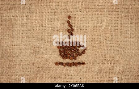 Konzeptuelles künstlerisches Stillleben des Kaffeetassen-Symbolmusters auf rustikalem Sackleinen-Stoff aus Kaffeebohnen Stockfoto