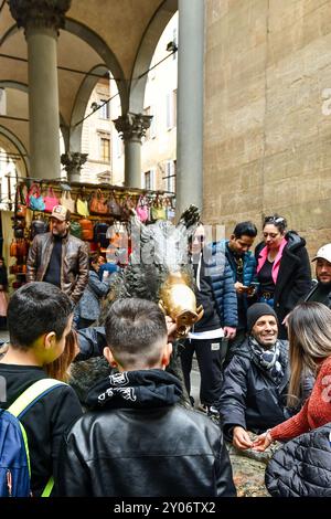 Touristen, die das Glücksritual am Porcellino-Brunnen in der Loggia des Mercato Nuovo oder Mercato del Porcellino, Florenz, Italien, verfolgen Stockfoto