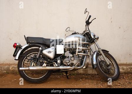 GOA, Indien - 27. Februar 2024: Ein silbernes Royal Enfield Bullet 350 Motorrad parkt in der Nähe einer Mauer. Stockfoto