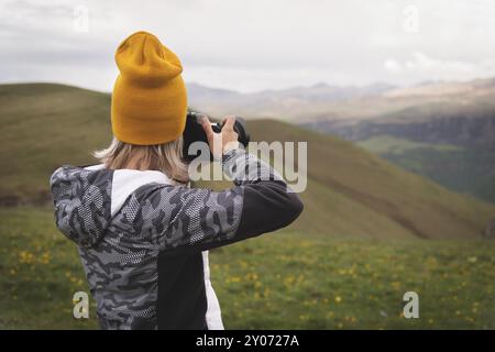 Ein junges Mädchen fotografiert an einem bewölkten Tag ein Plateau auf einem hohen Berg. Blick auf das Mädchen dahinter Stockfoto