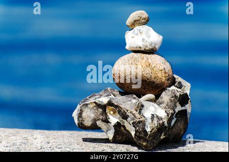 Steinpyramide am Strand vor blauem Wasser Stockfoto