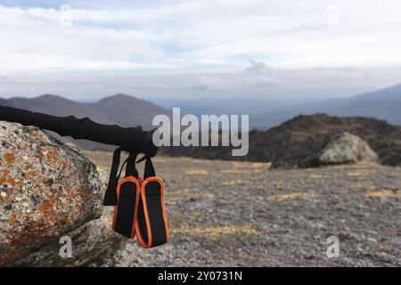 Professionelle Sticks zum Besteigen eines Berges in der Nähe eines Steines auf einem hohen Bergweg vor blauem Himmel und weißen Wolken. Das Konzept der aktiven Erholung Stockfoto