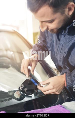 Nahaufnahme eines professionellen Windschutzscheibenreparateurs, der mit hydraulischem Polymer-Risspachtel arbeitet. Beseitigung von Rissen und Spänen an Windschutzscheiben Stockfoto