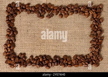 Horizontaler Rahmen aus aromatischen Kaffeebohnen auf Sackgewebehintergrund Stockfoto