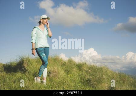 Fitness-Läuferin, die Musik über die Natur hört. Porträt eines schönen Mädchens mit Ohrhörern und Laufkappe. Vor dem Hintergrund von Stockfoto