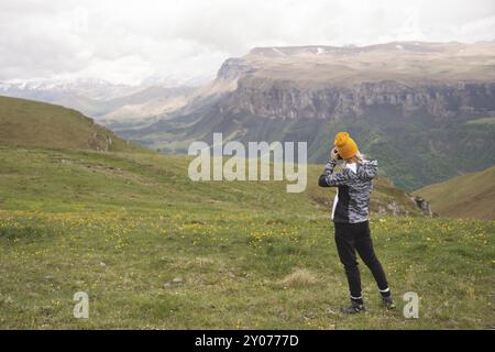 Ein junges Mädchen fotografiert an einem bewölkten Tag ein Plateau auf einem hohen Berg. Blick auf das Mädchen dahinter Stockfoto