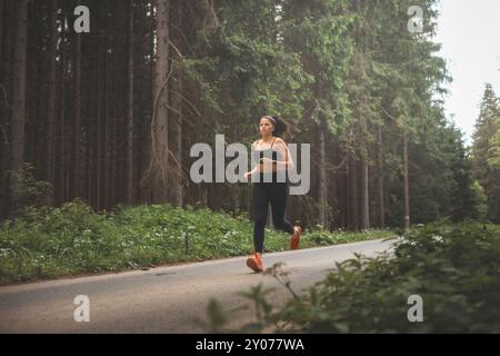 Brünette im Alter von 20-25 Jahren in schwarzer Sportbekleidung, die in der Abendsonne in der Natur läuft. Aktiver Lebensstil. Outdoor-Sport. Stockfoto