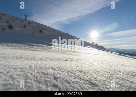 Die Landschaft der schneebedeckten kaukasischen Felsen am Gumbashi Pass. Unberührter Schnee unter der Vorsonne und dem Bergkamm im Hintergrund. Russland, Stockfoto