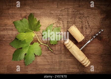Ein Weinblatt mit einem Vintage Korkenzieher und ein Wein Cork, Top Shot auf einem Holzschaft mit einem Platz für Text Stockfoto