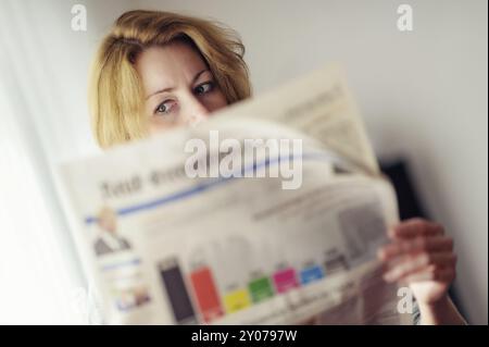 Die junge Frau liest eine Zeitung mit Vorhersagen für die Bundestagswahl Stockfoto