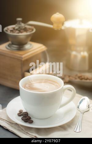 Kaffeetasse und eine alte Kaffeemühle mit Kaffeekanne auf einem alten Holztisch Stockfoto