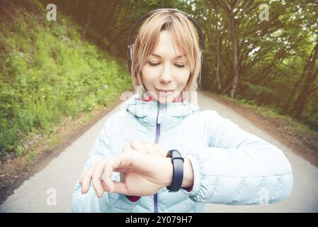 Porträt Junge Fitness-Frau, die ihre Smartwatch ansieht, während sie eine Pause vom Sporttraining macht. Sportsfrau überprüft Puls auf Fitness-Smartwatch d Stockfoto