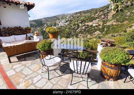 Tisch und Stühle am Aussichtspunkt des Cafés und Blick auf die Häuser aus der Luft im Dorf Makrinitsa in Pelion, Griechenland, Europa Stockfoto