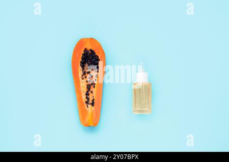 Papaya Frucht und kosmetische Serumflasche auf hellblauem Hintergrund. Draufsicht, flach. Stockfoto