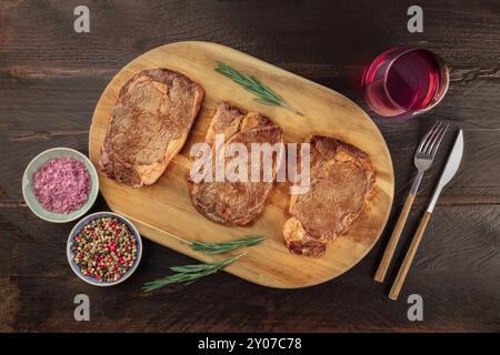 Rinderfilet Steaks, geschossen von oben auf einen dunklen Holzmöbeln im Landhausstil Hintergrund mit Rosmarin, Salz, Pfeffer, und Wein Stockfoto
