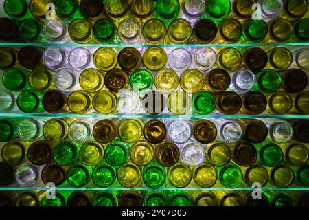 Natürlich beleuchtete, mehrfarbige Weinflaschen auf Glasregalen Stockfoto