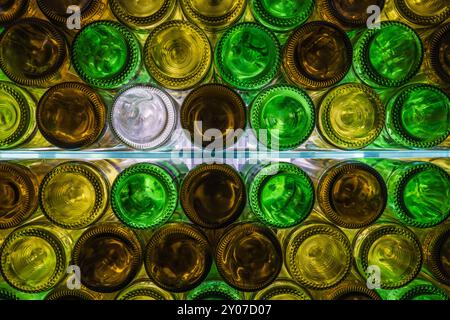 Natürlich beleuchtete, mehrfarbige Weinflaschen auf Glasregalen Stockfoto