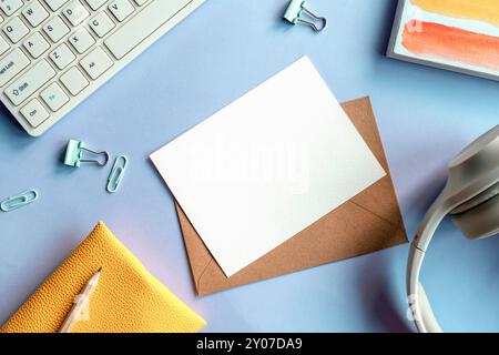 Leere Karte und Schulzubehör, Notizblock, Bleistift, Kopfhörer und Computertastatur auf blauem Hintergrund. Draufsicht, flach, Modell. Stockfoto