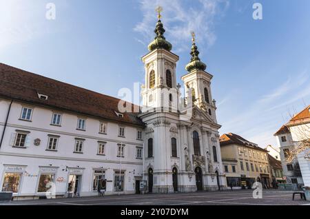 Österreich, 20.01.2019: Blick auf Kirche Mariahilf zwei Türme und Platz im Stadtzentrum in der Nähe der Mur, Wintersonne Reiseziel, Europa Stockfoto