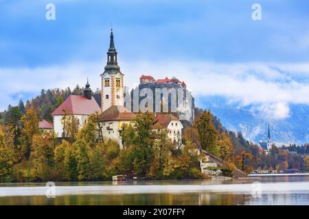 Morgen Blick auf den Bleder See mit der Kirche der Himmelfahrt der Maria, Slowenien und im Herbst bunte Bäume und Nebel Hintergrund Stockfoto