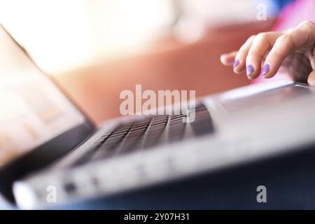 Mädchen mit violetten Fingernägeln benutzt ihren Laptop zu Hause auf der Couch Stockfoto