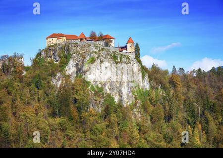 Mittelalterliche Burg auf dem Fels oben an der See Bled in Slowenien und im Herbst Bäume Wald Stockfoto