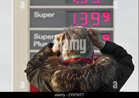 Frau, die vor der Preistafel einer Tankstelle steht Stockfoto