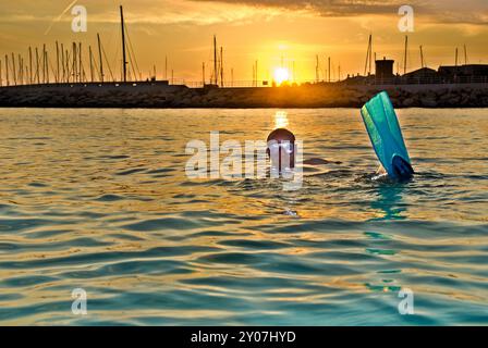 Mann mit Tauchbrille und Flossen im Meer vor der untergehenden Sonne Stockfoto