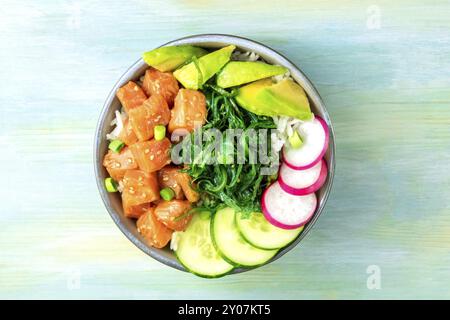 Poke Lachs mit Avocado, Wakame und Gurke, Schuß von oben auf eine hellblaue Hintergrund mit einem Platz für Text Stockfoto