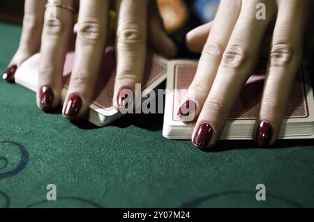 Hände eines Croupier-Händlers an einem Blackjack-Kartentisch, der die Karten in einem Casino mischt Stockfoto