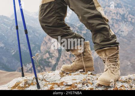 Nahaufnahme des Fußes eines Touristen in Trekkingschuhen mit Stöcken für Nordic Walking auf einem Felsstein in den kaukasischen Bergen Stockfoto