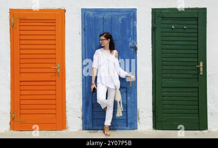 Junge Frau, die gegen bunte Türen steht. Lifestyle-Hintergrund Stockfoto