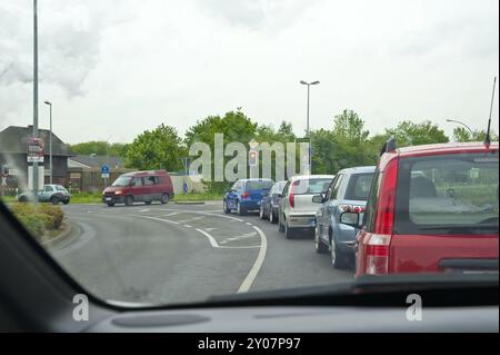 Autos, die am Bahnübergang geparkt sind und auf den Zug warten Stockfoto