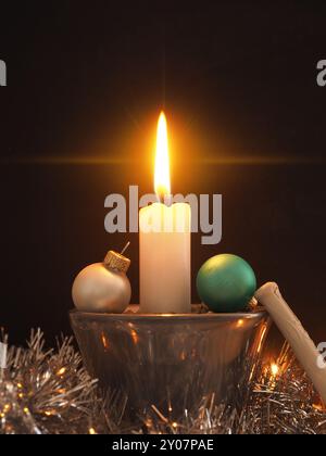 Erste Advent Kerzen brennen, eine Kerze mit Weihnachten Dekoration in Silber Stockfoto