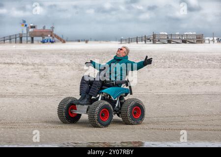 Mann im Strandrollstuhl, hebt Arme in Freude, Sankt-Peter-Ording, Schleswig-Hostein, Deutschland, Europa Stockfoto