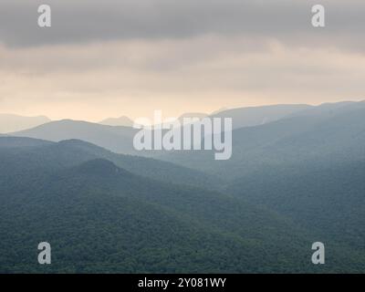 Ein atemberaubender Blick vom Gipfel des Mt. Van Hoevenberg, wo die Adirondack Mountains in Schichten durch einen nebeligen Dunst in der Nähe des Lake Placid, New, auftauchen Stockfoto