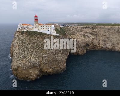 Ein roter Leuchtturm und weiße Gebäude stehen auf einer imposanten Klippe mit einem weiten Blick auf das Meer, aus der Vogelperspektive, Leuchtturm, Cabo de Sao Vicente, Kap St. V. Stockfoto