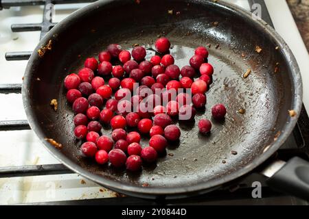 Ein Blick auf eine gefrorene Preiselbeere, die in einer Antihaftpfanne kocht. Stockfoto