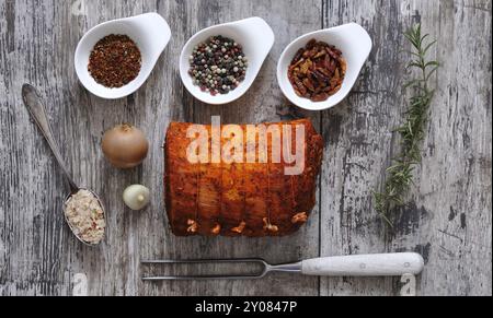 Gefüllter Schweinebauch mit Gewürzen. Gammonfleisch mit verschiedenen Gewürzen auf einem Holztisch Stockfoto