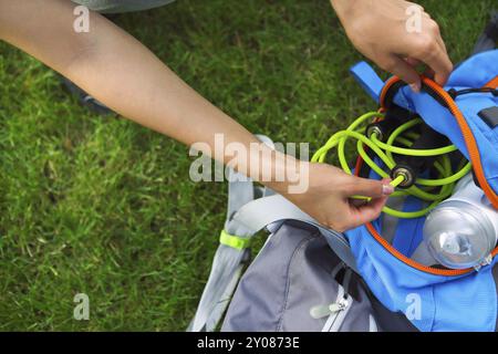 Sportliche Frau sitzt auf dem grünen Rasen mit Springseil, Rucksack und Trinkflasche. Nahaufnahme Stockfoto