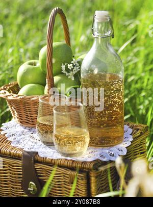 Apfelgetränk und Korb mit grünen Äpfeln im freien Stockfoto