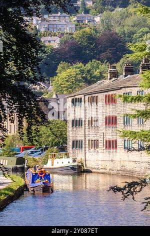 Canal Schmalboote vertäuten neben ehemaligen Weberhütten am Rochdale-Kanal in der Stadt Hebden Bridge England in Calderdale West Yorkshire Stockfoto
