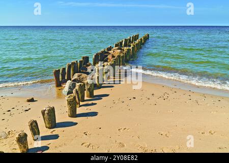 Alte hölzerne Wellenbrecher am schönen Sandstrand der Ostsee am sonnigen Tag Stockfoto