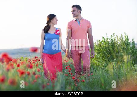 Portrait einer jungen schönen schwangeren Paare im Mohnfeld Stockfoto