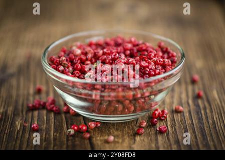 Rosa Pfeffer als detailreiche Nahaufnahme auf einem Vintage Holztisch, selektiver Fokus Stockfoto