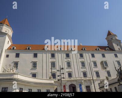 Frontalansicht eines großen weißen historischen Schlosses mit Türmen und einer Flagge auf dem Dach, bratislava, slowakei Stockfoto