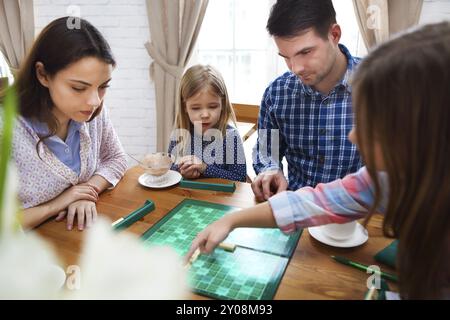 Glückliche junge Familie Plaing Brettspiel mit zwei Töchtern Stockfoto