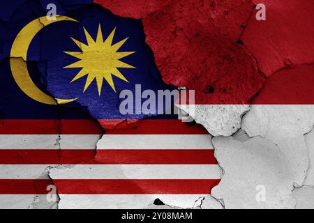 Flaggen von Malaysia und Indonesien auf gerissene Wand gemalt Stockfoto